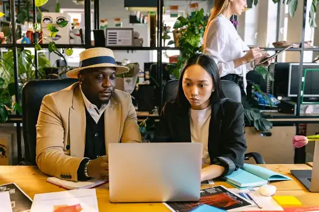 startup team collaborating around laptops in a bright modern office