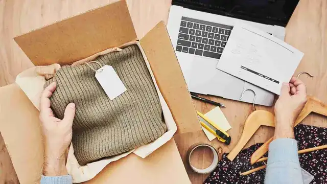 online store owner packing orders with laptop showing ecommerce dashboard