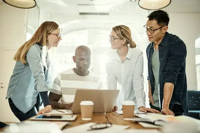 startup team collaborating around laptops in a bright modern office